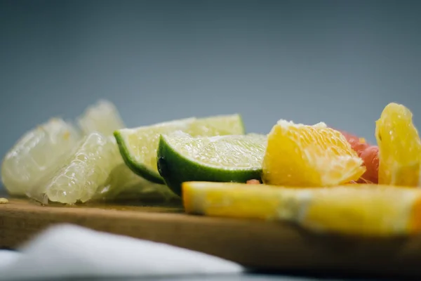 Pila de rodajas de cítricos. Naranjas y limones limas, pomelo, pomelo. Sobre mesa de madera — Foto de Stock