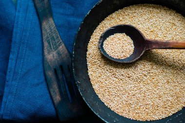 Bir kaşık tohum, doğal bir tahta kaşıkta, eski bir tavada, koyu renkli doğal ahşabın arka planına karşı.