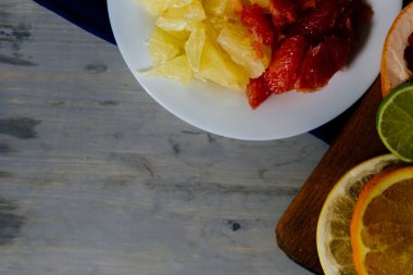 Çeşitli narenciye meyve dilimleri portakal, limon, limon, greyfurt, pomelo ve portakal suyu bir bardak kesti. Ahşap bir tahta ve bir vintag üzerine yayılmış