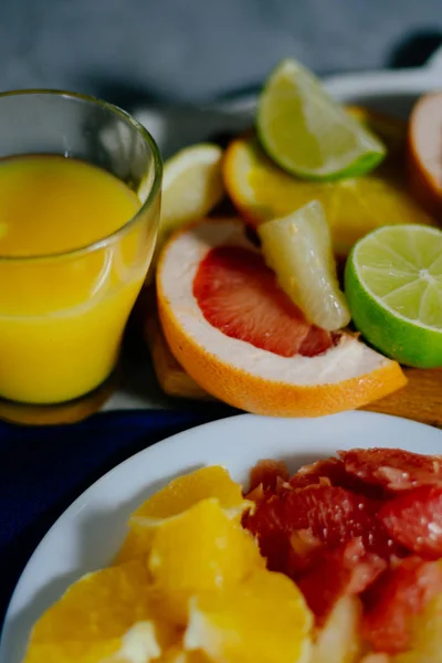 Various citrus fruit cut into slices orange, lemon, lime, grapefruit, pomelo and a glass of orange juice.
