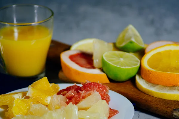 Various citrus fruit cut into slices orange, lemon, lime, grapefruit, pomelo and a glass of orange juice.
