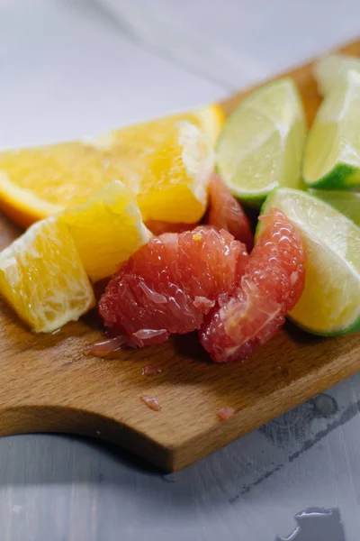 Pila de rodajas de cítricos. Naranjas y limones limas, pomelo, pomelo. Sobre mesa de madera — Foto de Stock