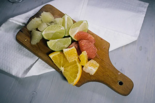 Pila de rodajas de cítricos. Naranjas y limones limas, pomelo, pomelo. Sobre mesa de madera — Foto de Stock