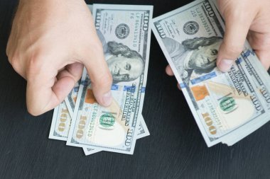 Beyaz genç adam para sayar, yüz yeni banknotlar siyah bir arka plan planı kapatın. İş ve finans kavramları. Üstten Görünüm .