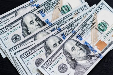 Bize yeni bir siyah ahşap dokulu masaya yüz dolarlık banknotlar. Yukarıdan görüntüleyin. Para ve finans kavramları