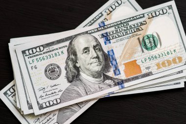 Bize yeni bir siyah ahşap dokulu masaya yüz dolarlık banknotlar. Yukarıdan görüntüleyin. Para ve finans kavramları