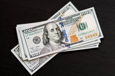 Bize yeni bir siyah ahşap dokulu masaya yüz dolarlık banknotlar. Yukarıdan görüntüleyin. Para ve Finans 100 $ kavramları
