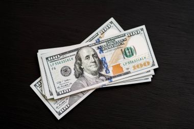 Bize yeni bir siyah ahşap dokulu masaya yüz dolarlık banknotlar. Yukarıdan görüntüleyin. Para ve Finans 100 $ kavramları