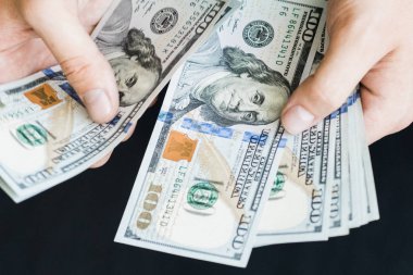 Beyaz genç adam para sayar, yüz yeni banknotlar siyah bir arka plan planı kapatın. İş ve finans kavramları. Üstten Görünüm .