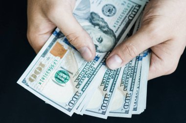 Beyaz genç adam para sayar, yüz yeni banknotlar siyah bir arka plan planı kapatın. İş ve finans kavramları. Üstten Görünüm .