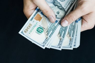 Beyaz genç adam para sayar, yüz yeni banknotlar siyah bir arka plan planı kapatın. İş ve finans kavramları. Üstten Görünüm .