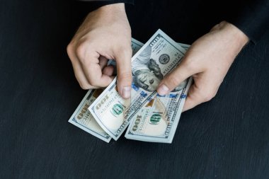 Beyaz genç adam para sayar, yüz yeni banknotlar siyah bir arka plan planı kapatın. İş ve finans kavramları. Üstten Görünüm .