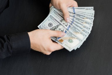 Beyaz genç adam para sayar, yüz dolar faturaları bir siyah arka plan yakın plan, Motion blur. İş ve finans kavramları. Üstten Görünüm 100 $