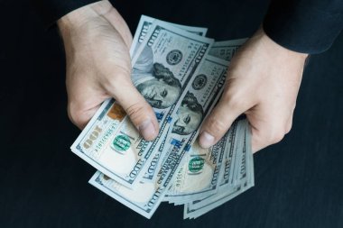 Beyaz genç adam para sayar, yüz yeni banknotlar siyah bir arka plan planı kapatın. İş ve finans kavramları. Üstten Görünüm .