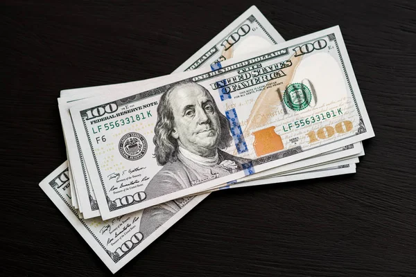 Bize yeni bir siyah ahşap dokulu masaya yüz dolarlık banknotlar. Yukarıdan görüntüleyin. Para ve Finans 100 $ kavramları
