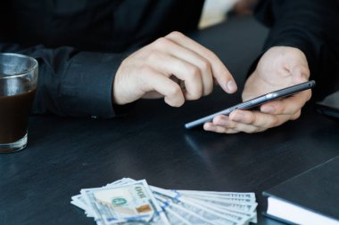 Teknoloji, online bankacılık, para transferi, e-ticaret kavramı. Kullanma smartphone dolarlarına gri duvar arka plan üzerinde uçan iş adamı. Internet kazanç kavramı