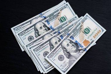 Bize yeni bir siyah ahşap dokulu masaya yüz dolarlık banknotlar. Yukarıdan görüntüleyin. Para ve finans kavramları
