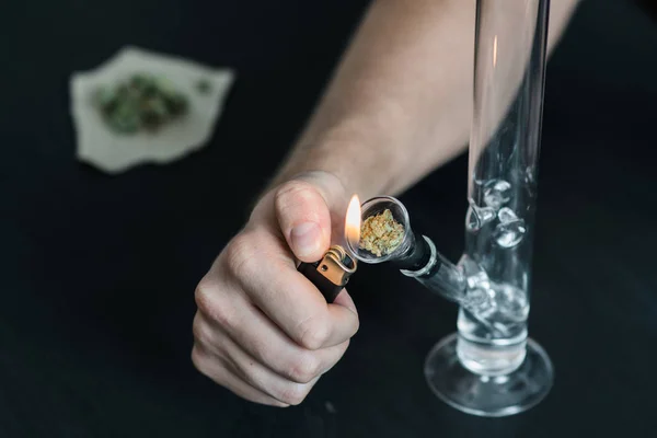 Mann raucht mit Bong und medizinischem Marihuana, Cannabis thc flower sativa und Indica aus nächster Nähe auf schwarzem Hintergrund. Lifestylekonzepte zur Legalisierung von Marihuana in der Welt und den Vereinigten Staaten. — Stockfoto