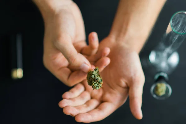 In Hands of a man medical marijuana, cannabis, Bong and thc flower Sativa and Indica Close up on a black background. lifestyle Concepts the legalization of marijuana in the world and the United States — Stock Photo, Image