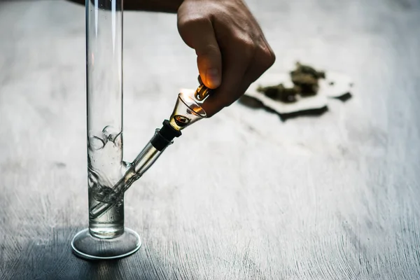 Mann raucht mit Bong und medizinischem Marihuana, Cannabis thc flower sativa und Indica aus nächster Nähe auf schwarzem Hintergrund. Lifestylekonzepte zur Legalisierung von Marihuana in der Welt und den Vereinigten Staaten. — Stockfoto