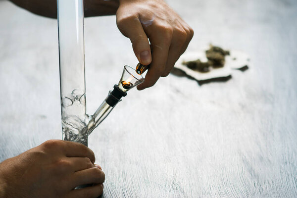 man smokes using Bong and medical marijuana, cannabis thc flower Sativa and Indica Close up on a black background. lifestyle Concepts the legalization of marijuana in the world and the United States.