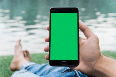 chroma anahtar yeşil ekran ile mobil akıllı telefon gren arka planda tutan adamın yakın çekim el