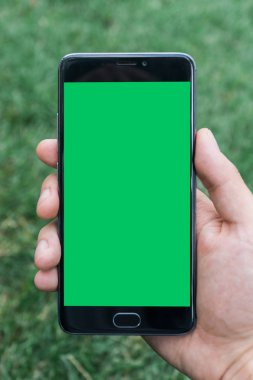 chroma anahtar yeşil ekran ile mobil akıllı telefon gren arka planda tutan adamın yakın çekim el 