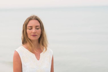 okyanus kıyısında yatay görüntü üzerinde Beyaz giysili bir yaşam tarzı kadına portre