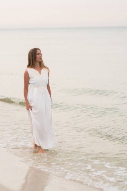 Dikey yaşam tarzı kadın beyaz bir elbise Okyanusu kıyısında ayakta vurdu