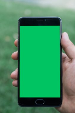 chroma anahtar yeşil ekran ile mobil akıllı telefon gren arka planda tutan adamın yakın çekim el