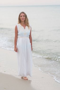 Dikey yaşam tarzı kadın beyaz bir elbise Okyanusu kıyısında ayakta vurdu