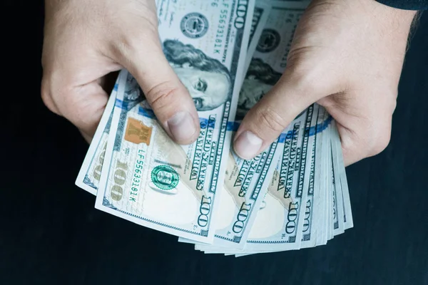 Beyaz genç adam para sayar, yüz yeni banknotlar siyah bir arka plan planı kapatın. İş ve finans kavramları. Üstten Görünüm .