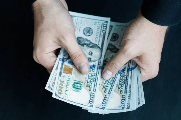 Beyaz genç adam para sayar, yüz yeni banknotlar siyah bir arka plan planı kapatın. İş ve finans kavramları. Üstten Görünüm .