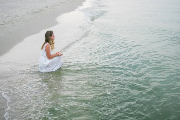 Lifestyle woman in a white dress sitting on the ocean coast — Stock Photo, Image