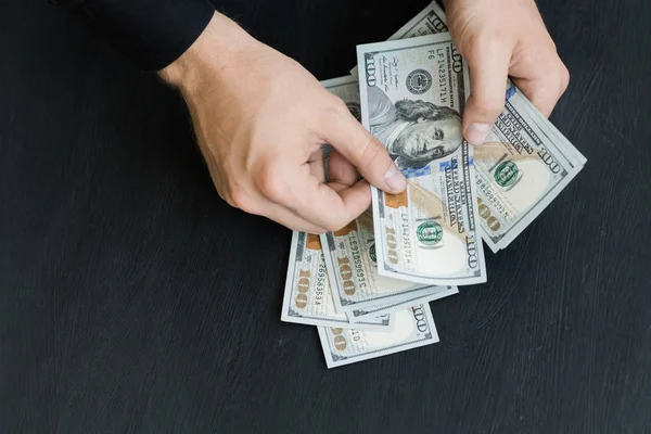 Beyaz genç adam para sayar, yüz yeni banknotlar siyah bir arka plan planı kapatın. İş ve finans kavramları. Üstten Görünüm