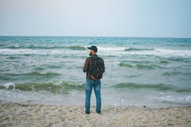 Genç Beyaz turist adam okyanusun arka planı şafakta sahanın. Turizm ve yaşam tarzı kavramları
