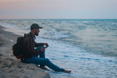 Kumlu plaj arka plan üzerinde hareket eden smartphone kullanarak adam turist. Çevrimiçi bağlantı, iletişim mesajlaşma, bankacılık için fotoğraf konsepti..