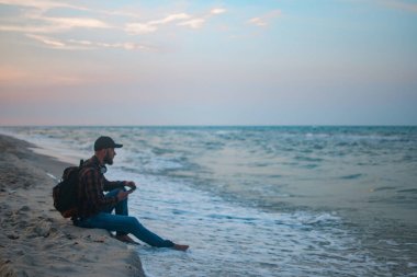 Kumlu plaj arka plan üzerinde hareket eden smartphone kullanarak adam turist. Çevrimiçi bağlantı, iletişim mesajlaşma, bankacılık için fotoğraf konsepti..
