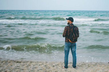 Genç Beyaz turist adam okyanusun arka planı şafakta sahanın. Turizm ve yaşam tarzı kavramları