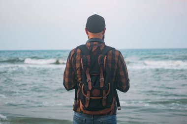 Genç Beyaz turist adam okyanusun arka planı şafakta sahanın. Turizm ve yaşam tarzı kavramları