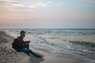 Kumlu plaj arka plan üzerinde hareket eden smartphone kullanarak adam turist. Çevrimiçi bağlantı, iletişim mesajlaşma, bankacılık için fotoğraf konsepti..