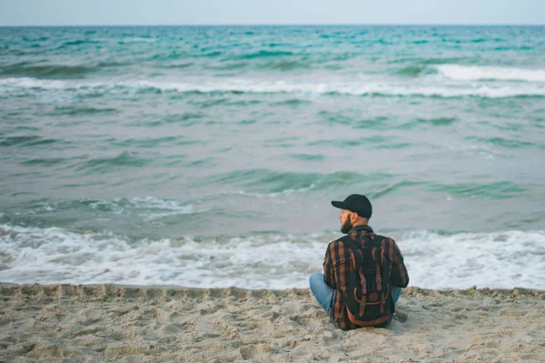 Mladé bílé turisty muž sedící na pozadí oceánu za svítání. Koncepce cestovního ruchu a životního stylu — Stock fotografie