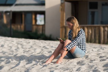 Bir smartphone deniz sahil kum içinde belgili tanımlık geçmiş yakınındaki plajda elinde tutan güzel kız