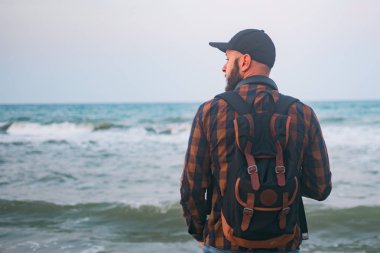 Genç bir beyaz turist okyanus arka planı şafakta duruyor. Turizm yaşam tarzının kavramlar