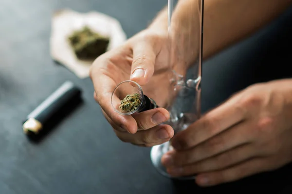 Τα χέρια ενός ανθρώπου Bong, ιατρική μαριχουάνα, thc λουλούδι κάνναβης Sativa και Indica στενή επάνω σε μαύρο φόντο. Lifestyle έννοιες στη νομιμοποίηση της μαριχουάνα στον κόσμο και την Ελλάδα. — Φωτογραφία Αρχείου
