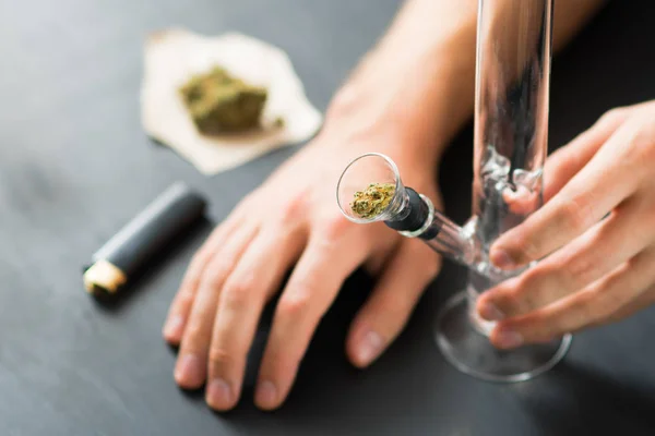 Hands of a man on Bong and medical marijuana, cannabis thc flower Sativa and Indica Close up on a black background. lifestyle Concepts the legalization of marijuana in the world and the United States. — Stock Photo, Image