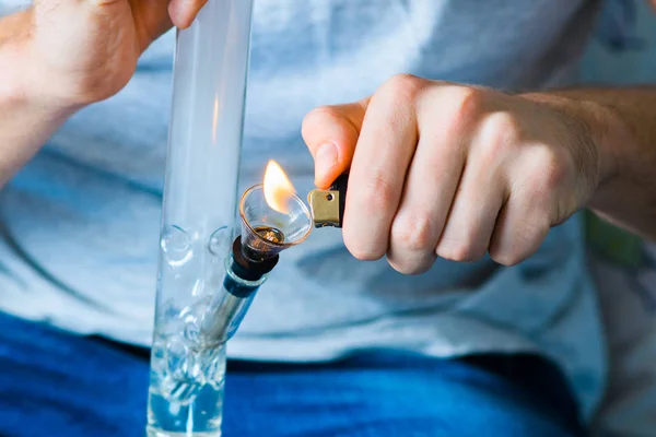 Man rookt met behulp van Bong en medische marihuana, cannabis thc flower Sativa en Indica sluit omhoog op een zwarte achtergrond. lifestyle concepten de legalisatie van marihuana in de wereld en de Verenigde Staten. — Stockfoto