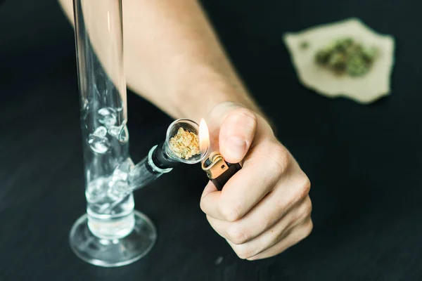 Homme fume en utilisant Bong et de la marijuana médicale, cannabis thc fleur Sativa et Indica Gros plan sur un fond noir. lifestyle Concepts la légalisation de la marijuana dans le monde et aux États-Unis . — Photo