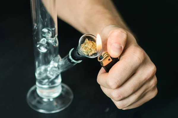 Pria merokok menggunakan Bong dan mariyuana medis, bunga ganja Sativa dan Indica Tutup pada latar belakang hitam. Gaya hidup menerima legalisasi ganja di dunia dan Amerika Serikat . — Stok Foto