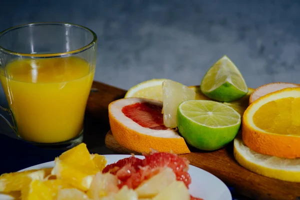 다양 한 감귤 류 과일 슬라이스 오렌지, 레몬, 라임, 자 몽, 포 멜로 오렌지 주스의 유리를 잘라. 나무 보드와 빈티지 화이트 접시에 밖으로 확산 — 스톡 사진